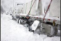 Schnee in Kalifornien: Ein Lkw-Fahrer versucht die Reifen seines Lkw freizuschaufeln. - © Carlos Avila Gonzalez/San Francisco Chronicle via AP/dpa