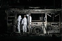 Israelische Polizeibeamte inspizieren einen der drei leeren Busse, die in dem südlichen Vorort von Tel Aviv explodiert sind. - © Ohad Zwigenberg/AP/dpa