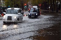Taxis fahren über eine überschwemmte Straße in London. - © Vuk Valcic/ZUMA Press Wire/dpa