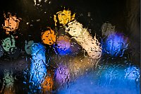 Regentropfen, die im Süden von Baden-Württemberg auf eine Windschutzscheibe prasseln, werden vom Licht der Straßenlampen angestrahlt. - © Felix Kästle/dpa