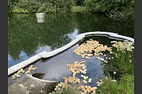 Mitarbeiter des Abwasserwerks legen sogenannte Ölschlängel und Ölbindemittel auf der Wasseroberfläche aus. - © Freiwillige Feuerwehr Leopoldshöhe