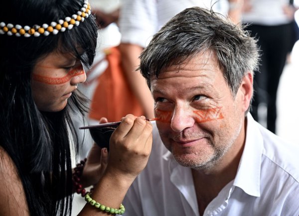 Ein Symbol des Willkommens und des Schutzes: Ein Mädchen malt Bundeswirtschaftsminister Robert Habeck mit einer rötlichen Naturfarbe ein Zeichen unter die Augen. - © Britta Pedersen/dpa