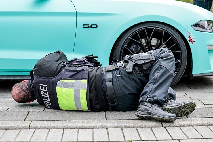Ein Polizeibeamter sichtet am «Car-Freitag» die Unterseite eines Fahrzeug auf dem Corneliusplatz in Düsseldorf. - © Thomas Banneyer/dpa