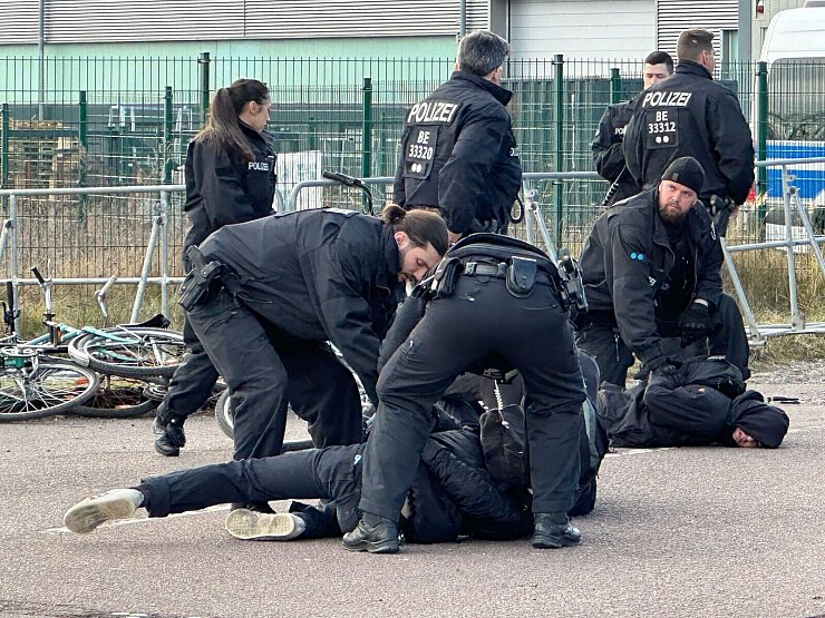 Polizisten halten Demonstranten am Boden fest. Sie hatten zuvor versucht mit Fahrrädern Richtung Veranstaltungshalle vorzudringen. - © Jörg Ratzsch/dpa