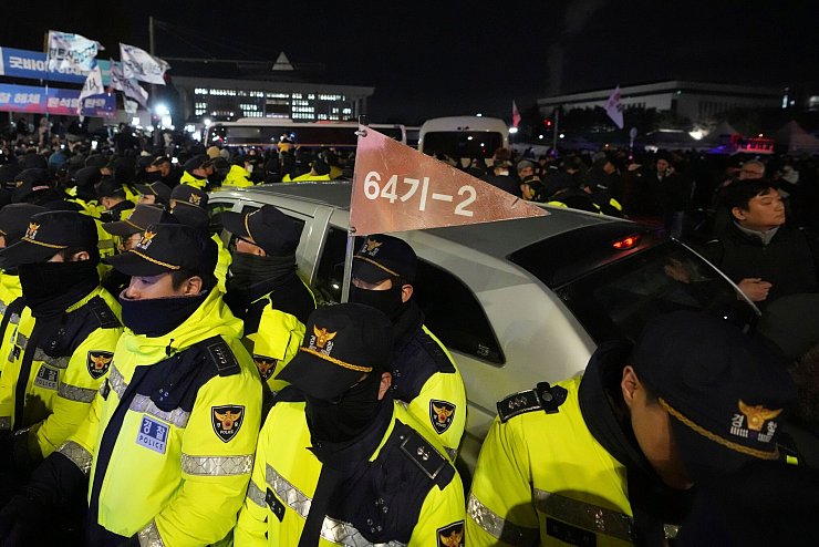 Polizisten vor dem Parlament schützten Militärfahrzeuge. - © Lee Jin-man/AP/dpa