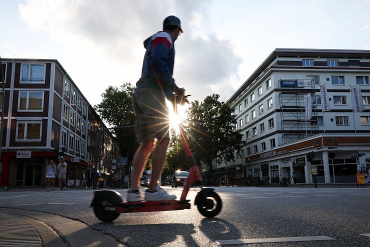 Ein Mann fährt auf einem E-Tretroller. - © Christian Charisius/dpa