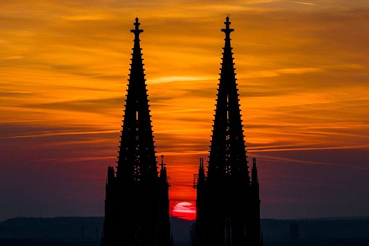 Die untergehende Sonne lässt den Himmel hinter dem Kölner Dom in orange-rot leuchten. - © Christoph Reichwein/dpa