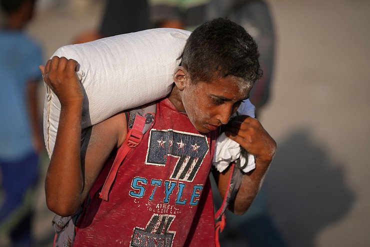 Ein palästinensischer Junge trägt einen Sack Mehl. (Archivbild) - © Jehad Alshrafi/AP/dpa