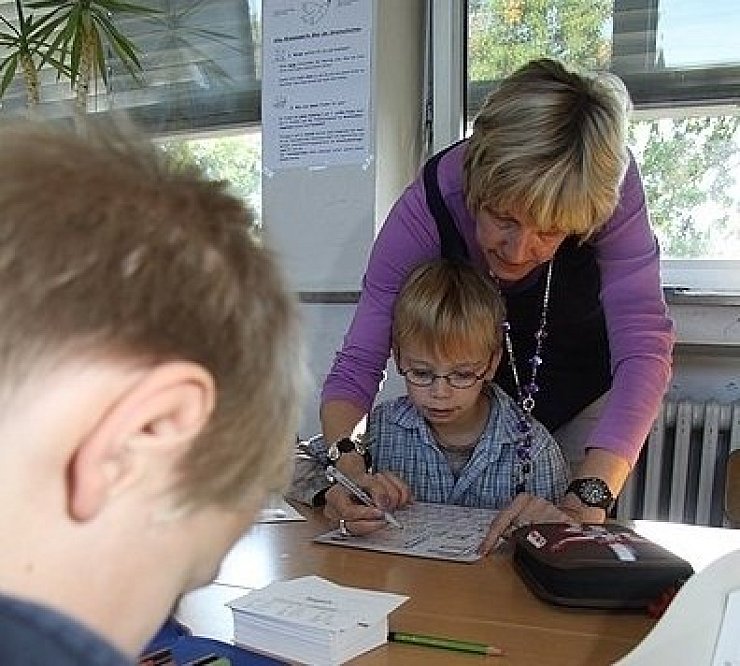 Lehrerin Cornelia Hartmann übt mit einem ihrer Schützlinge gezielt im Sprachunterricht der Grundschule Asemissen, ein weiterer Schüler arbeitet selbstständig an seinen Aufgaben. - © FOTO: LAHR