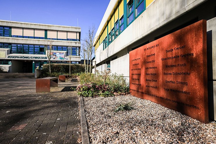 Am Joseph-König-Gymnasium steht eine Gedenktafel direkt am Schulhof, davor wird in den Pausen getobt und gelacht - ein Symbol dafür, dass die Toten weiterhin Teil der Schule sind. - © Oliver Berg/dpa