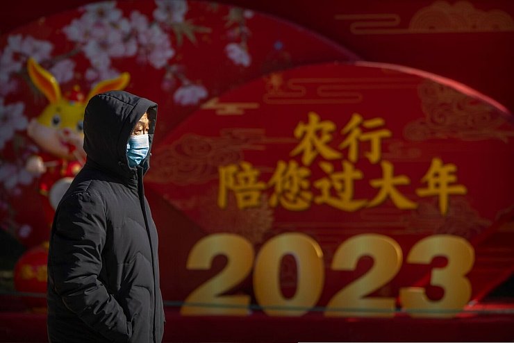 Ein Mann mit Mund-Nasen-Schutz läuft in einem öffentlichen Park in Peking an einem Plakat zum chinesischen Neujahr vorbei. - © Mark Schiefelbein/AP/dpa