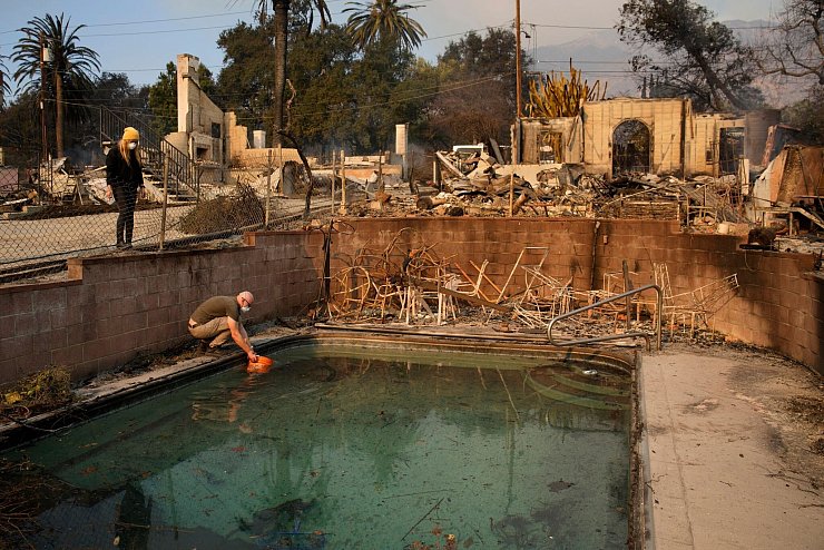 Robert Karban füllt einen Eimer mit Wasser aus einem Swimmingpool. - © John Locher/AP/dpa