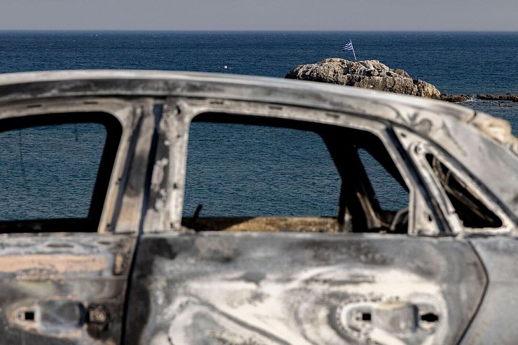 Ein verbranntes Fahrzeug auf der Insel Rhodos. - © Christoph Reichwein/dpa