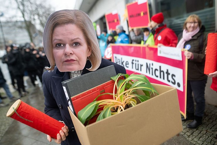 Eine Aktivistin demonstriert mit einer Maske von Bundesinnenministerin Nancy Faeser. - © Sebastian Christoph Gollnow/dpa