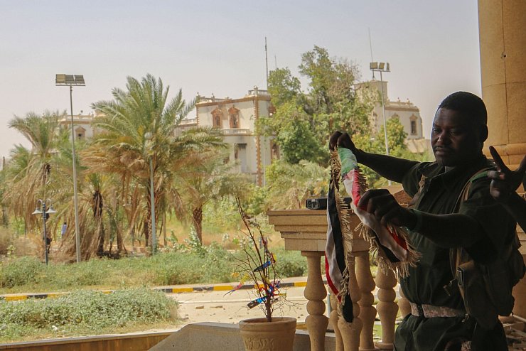 Ein sudanesischer Soldat mit der Nationalfahne nach der Rückeroberung des Präsidentenpalasts in Khartum - © Uncredited/AP/dpa