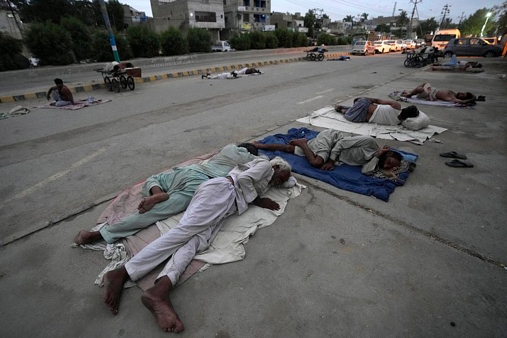 Arbeiter schlafen am Straßenrand an einem heißen Sommermorgen in Karatschi. - © Fareed Khan/AP/dpa