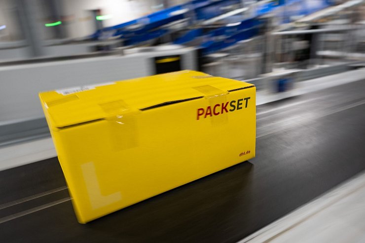 Ein Paket rollt über das Laufband eines DHL-Paketzentrums. - © Christophe Gateau/dpa
