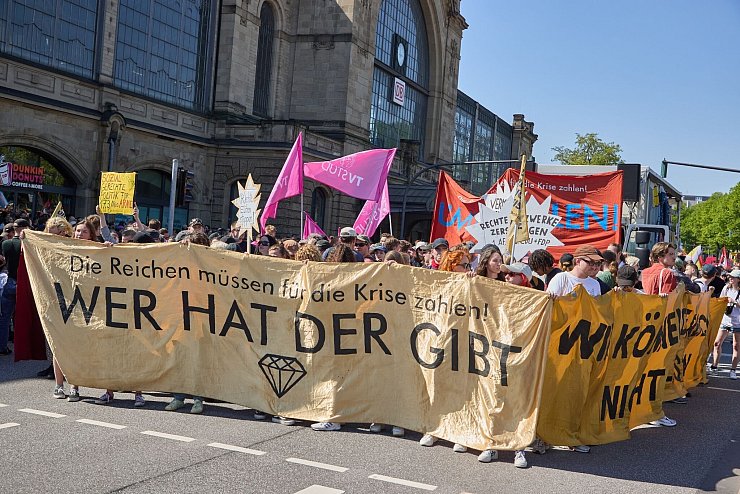 Teilnehmer der Demonstration «Wir haben die Scheiße so satt» vom Bündnis «Wer hat, der gibt» halten am Bahnhof Dammtor ein Transparent mit der Aufschrift: «„Die Reichen müssen für die Krise zahlen! Wer hat, der gibt“.» - © Georg Wendt/dpa