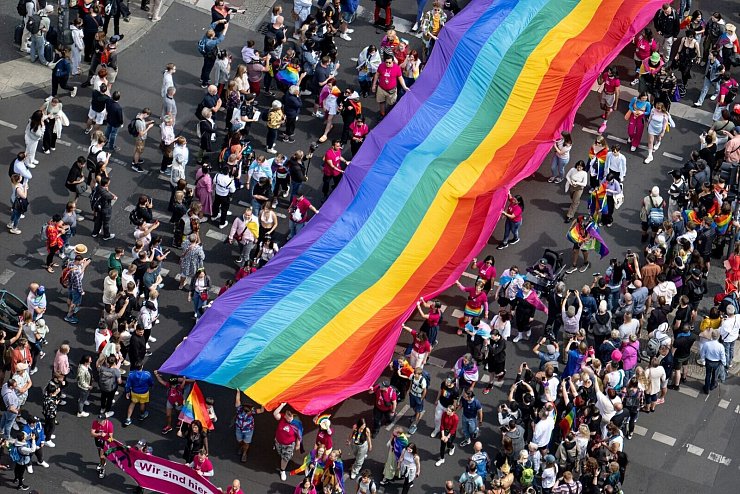 Menschen ziehen mit einer überdimensionalen Regenbogenfahne durch die Stadt. - © Fabian Sommer/dpa