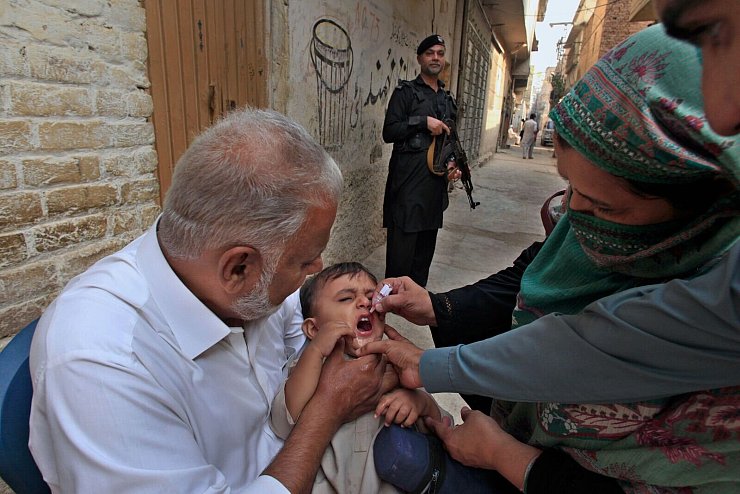 Impf-Teams in Pakistan werden von bewaffneten Männern bewacht, weil sie oft Ziel von Anschlägen sind. (Archivbild) - © Mohammad Sajjad/AP/dpa