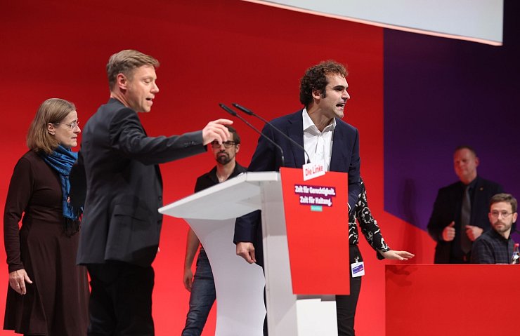 Eklat auf offener Bühne: Bijan Tavassoli (r) nutzte seine Bewerbungsrede für eine Beschimpfung der Linken und eine Lobrede auf Sahra Wagenknecht - und erklärte zum Abschluss seiner Rede seinen Parteiaustritt. - © Karl-Josef Hildenbrand/dpa