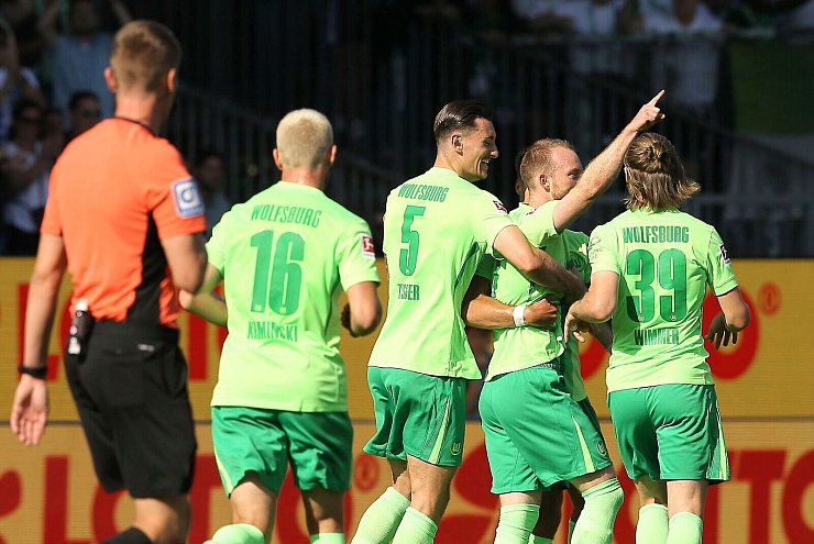 Wolfsburgs Maximilian Arnold (2.vr) bejubelt sein Tor zum 0:1. Die Rote Karte für Kiels Trainer Marcel Rapp sorgt für Diskussionen. - © Claus Bergmann/dpa