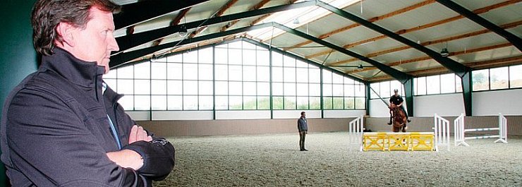 Üben in der neuen Halle: Unternehmer Klaus Röpke beobachtet Betriebsleiter und Springreiter Henrik Griese beim Training mit Maik Schlingheider auf dem Pferd "Caprys". - © Foto: Seda Hagemann
