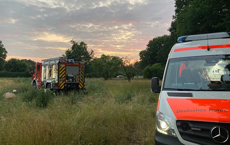 Fahrzeuge von Feuerwehr und Deutsches Rotes Kreuz stehen an einer Wiese. - © Christiane Bosch/dpa