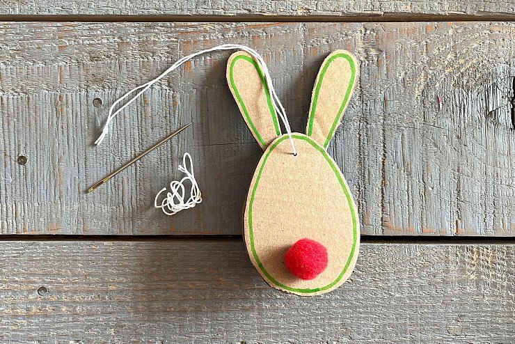 Bunte Bommel befestigen, mit einem Stift die Konturen umfahren und am Ende mit der Nadel einen Faden zum Aufhängen befestigen. - © DIY Academy/dpa-tmn