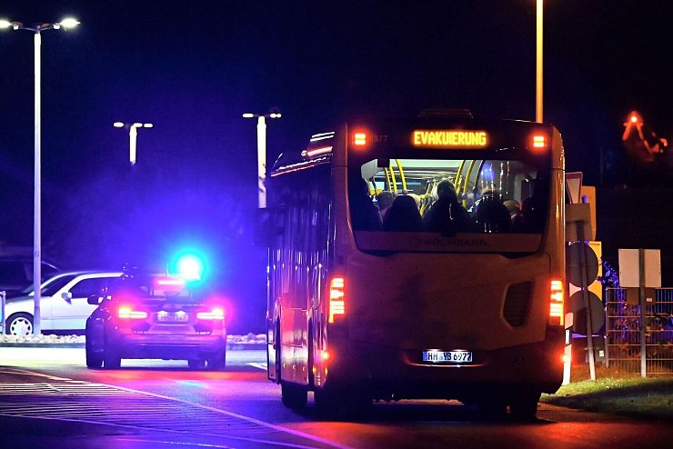 Ein Polizeiauto eskortiert einen Bus mit Menschen vom Flughafen Hamburg. - © Jonas Walzberg/dpa
