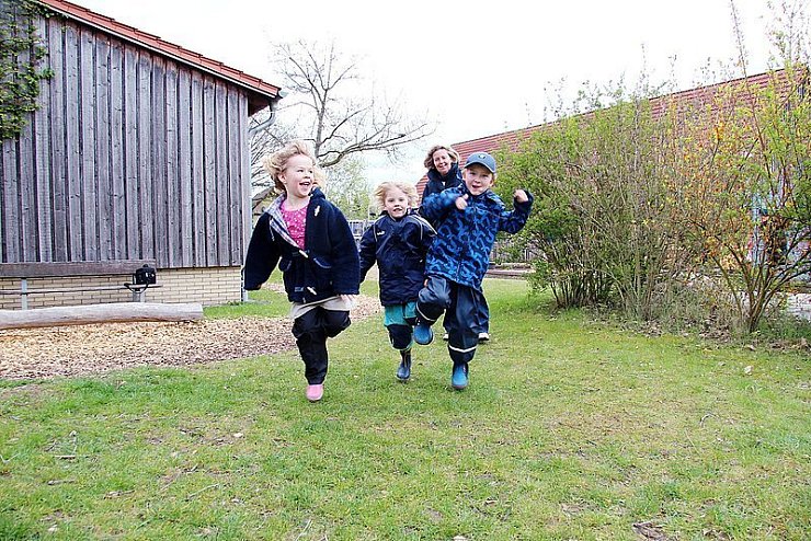 Alina, Alicia und Lukas (von links) hüpfen auf einem Bein über das Gelände des Kindergartens in Kirchheide. Leiterin Annette Hahmeier beobachtet die Sechsjährigen. - © Foto: Strathmann