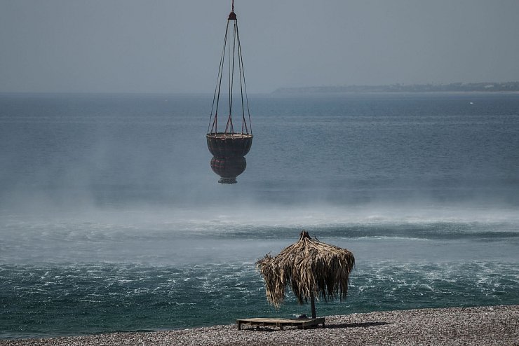 Ein Hubschrauber füllt in der Nähe des Dorfes Gennadi einen Korb mit Wasser aus dem Meer auf. - © Petros Giannakouris/AP/dpa
