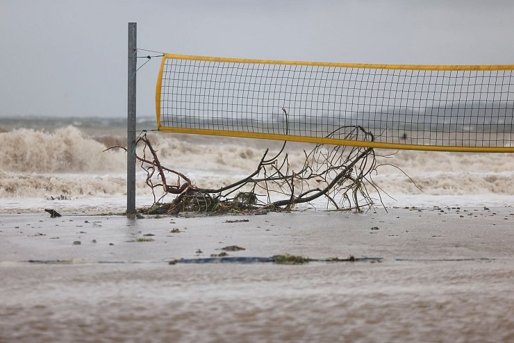 Ein entwurzelter Baum liegt unter einem Volleyballnetz am Ostseestrand von Eckernförde. - © Frank Molter/dpa