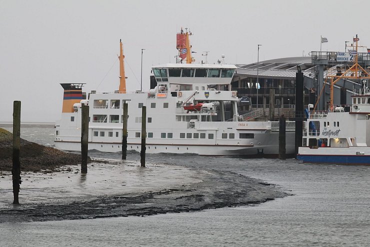 Eine Fähre liegt bei Niedrigwasser im Hafenbecken der Insel Norderney. - © Volker Bartels/dpa