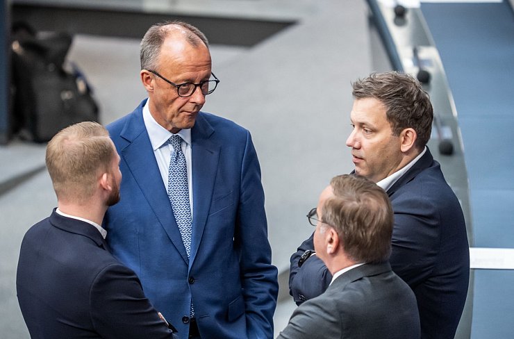 Versöhnliche Tonlage: Kanzler Merz spricht mit SPD-Generalsekretär Klüssendorf (links) und SPD-Chef Klingbeil (ganz rechts) im Bundestag. (Archivbild) - © Michael Kappeler/dpa