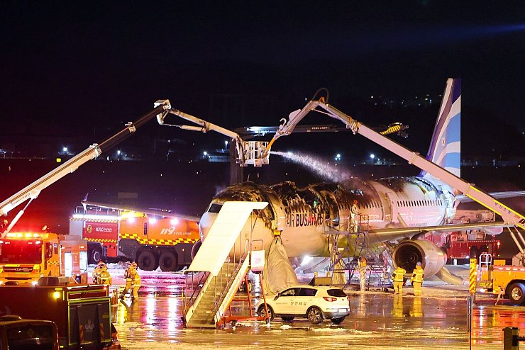 Flugzeug im südkoreanischen Busan geht in Flammen auf. Feuerwehrleute arbeiten daran, ein Feuer in einem Flugzeug der Air Busan am Gimhae International Airport zu löschen. - © Son Hyung-joo/Yonhap/AP/dpa