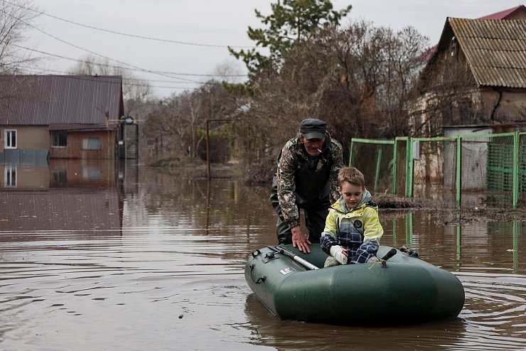 Ein Mann schiebt ein Schlauchboot mit einem Jungen in einem überfluteten Gebiet in Orenburg, Russland. - © Uncredited/AP