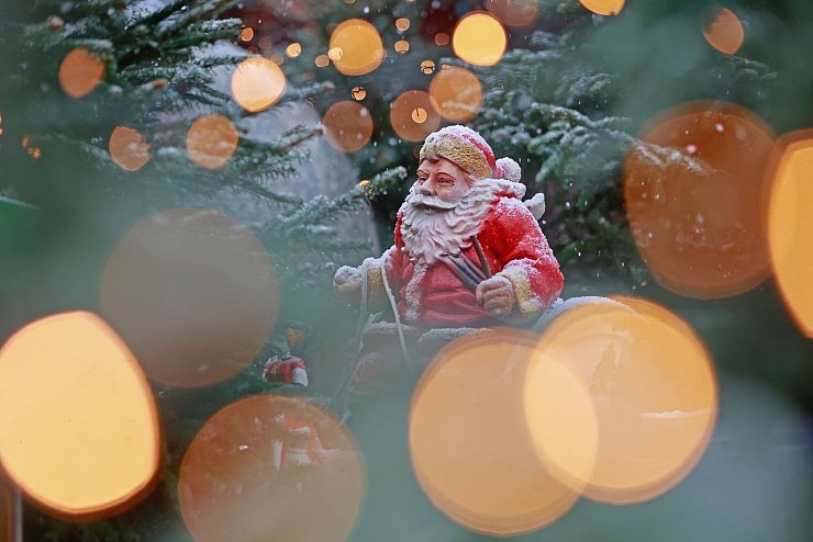 Weihnachtliches in Sachsen-Anhalt: Blick durch eine Lichterkette auf eine schneebedeckte Weihnachtsmannfigur. - © Matthias Bein/dpa