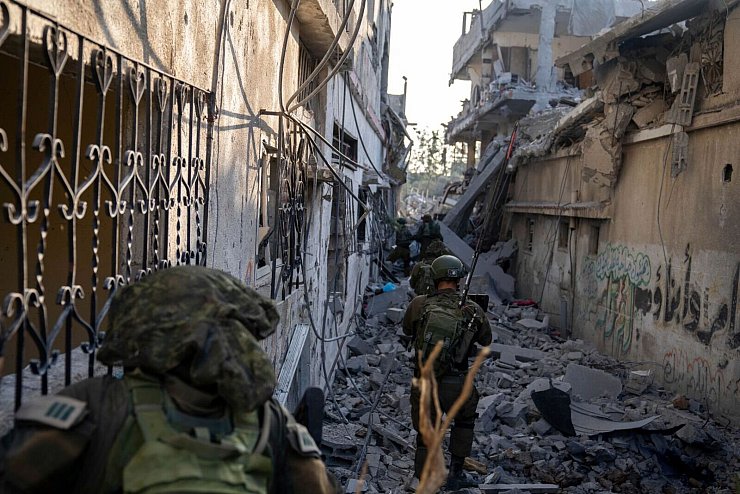 Israelische Soldaten gehen zwischen zerstörten Häusern: Israels Militär hat nach eigenen Angaben die Stadt Gaza umstellt. - © HO/Israel Defense Forces/AP/dpa