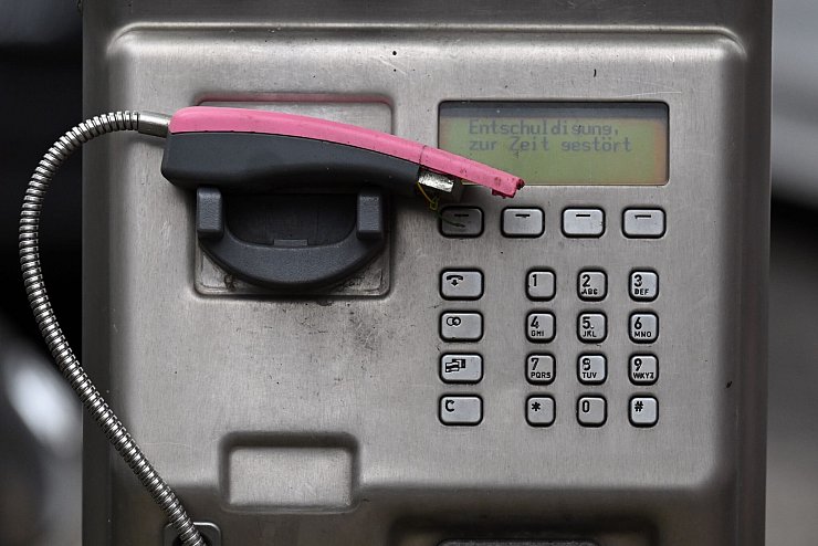 Ein abgebrochener Telefonhörer liegt in der Halterung eines deaktivierten Fernsprechers. - © Federico Gambarini/dpa
