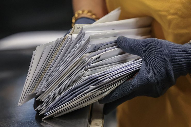 Eine Mitarbeiterin von DHL sortiert Briefe im Briefverteilzentrum. - © Oliver Berg/dpa