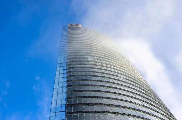 Nebelschwaden ziehen an der Zentrale von DHL, dem Posttower, vorbei. Oben angebracht ist ein Posthorn-Logo. - © Thomas Banneyer/dpa