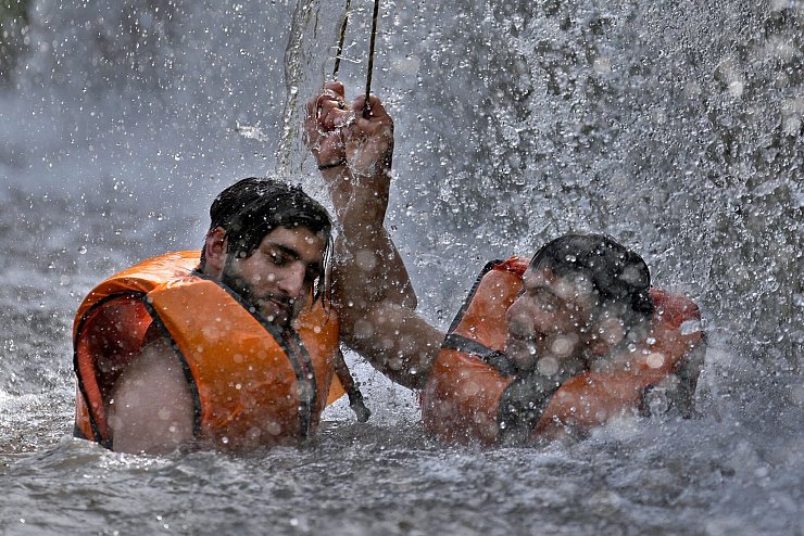 Pakistanische Männer kühlen sich in einem Bach ab, während die Temperaturen in Islamabad 39 Grad Celsius erreichen. - © Anjum Naveed/AP/dpa