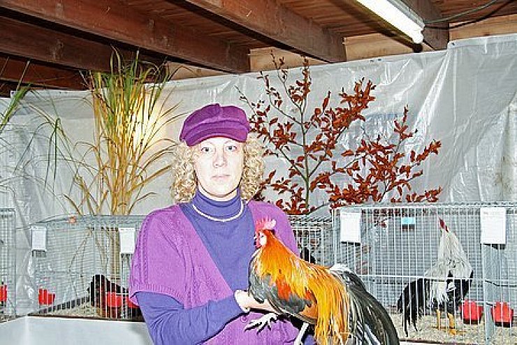 Farbenfroh: Ausstellungsleiterin Christa Rüsenberg mit Hahn.Foto: Blum