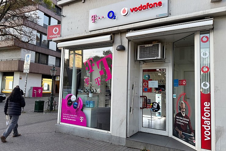 Eine Passantin geht in einer Fußgängerzone an einem Shop vorbei, der Mobilfunkverträge der drei etablierten deutschen Netzbetreiber Telekom, Telefónica O2 und Vodafone anbietet. Im Wettkampf um die Kundengunst bieten nun alle drei Anbieter Privatkunden reines 5G an, auch 5G SA genannt. - © Wolf von Dewitz/dpa