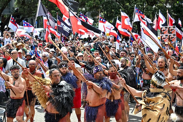 Demonstranten tragen die traditionelle Kleidung der indigenen Bevölkerung und präsentieren die Maori-Flagge, - © Mark Tantrum/AP
