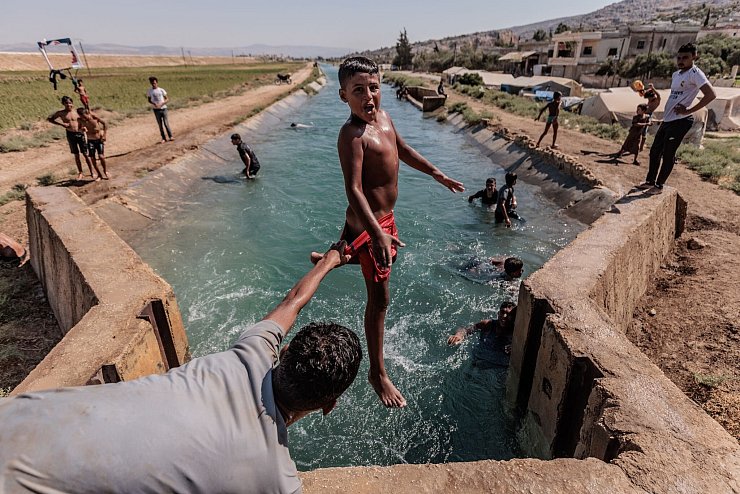 Das Foto des dpa-Fotografen Anas Alkharboutli zeigt syrische Jugendliche bei einer Abkühlung von der Hitze. - © Anas Alkharboutli/dpa
