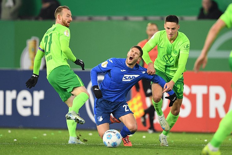 Schmerzhaft: Die Wolfsburger Maximilian Arnold (l) und Joakim Maehle stoppen Hoffenheims Torjäger Andrej Kramaric. - © Swen Pförtner/dpa