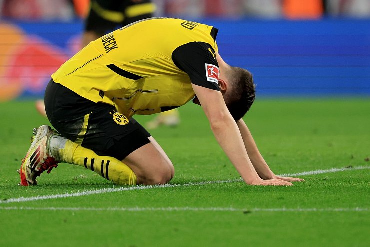 Nationalspieler Nico Schlotterbeck kniet auf dem Leipziger Rasen. - © Jan Woitas/dpa