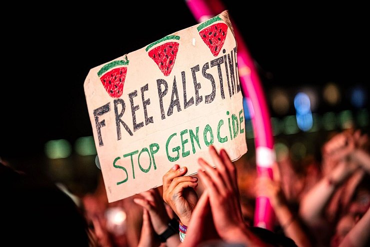 «Free Palestine - Stop Genocide» steht auf einem Plakat bei dem Auftritt vom US-Rapper Macklemore. Es war eine von wenigen politischen Botschaften im Publikum. - © Sina Schuldt/dpa